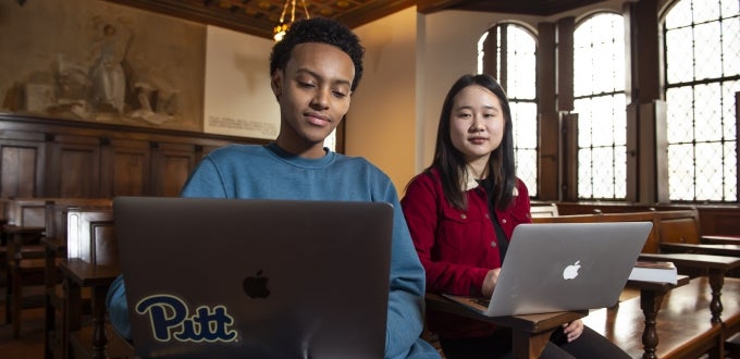 Two students with laptops in Nationality Room