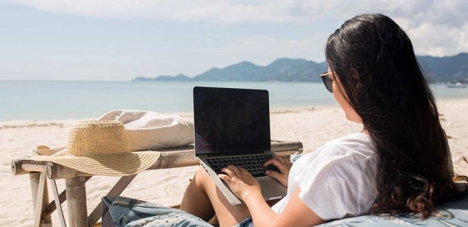 Girl on laptop at the beach