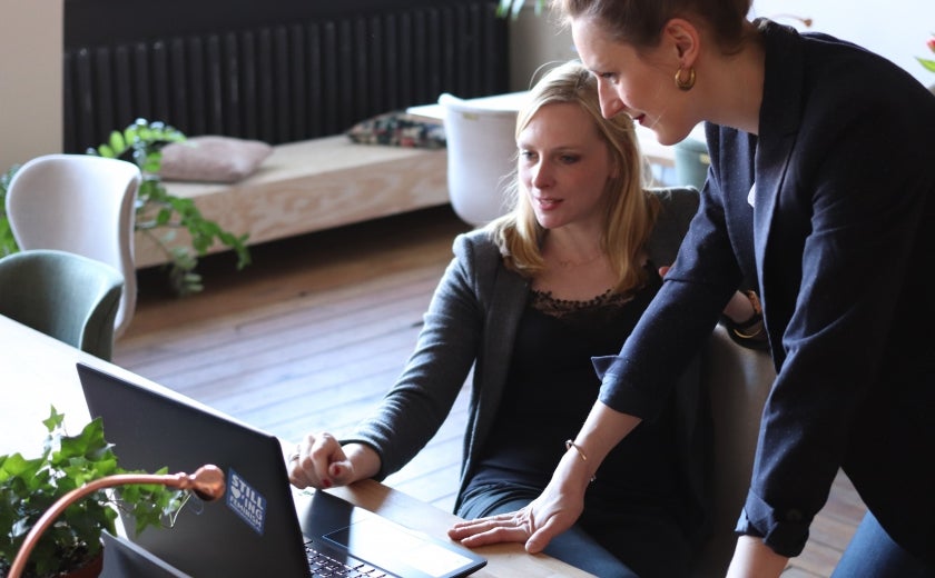 woman showing another woman something on her laptop