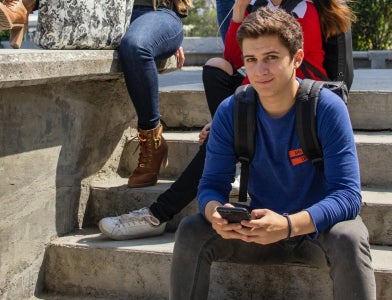 Student on phone looking into camera