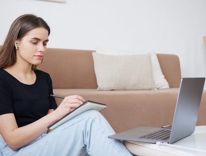 woman taking notes and using laptop
