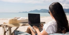 Girl on laptop at the beach